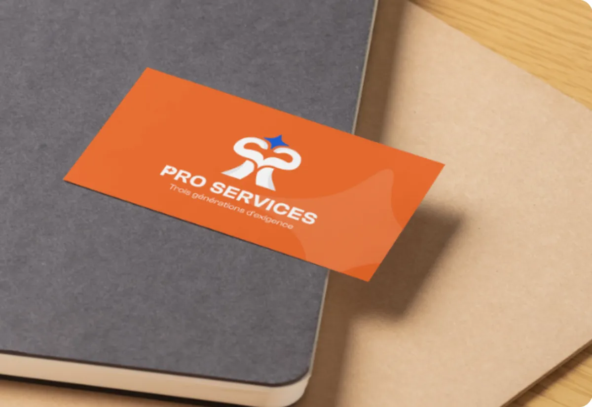 Carte de visite Pro Services, logo blanc sur fond orange, posée sur un carnet