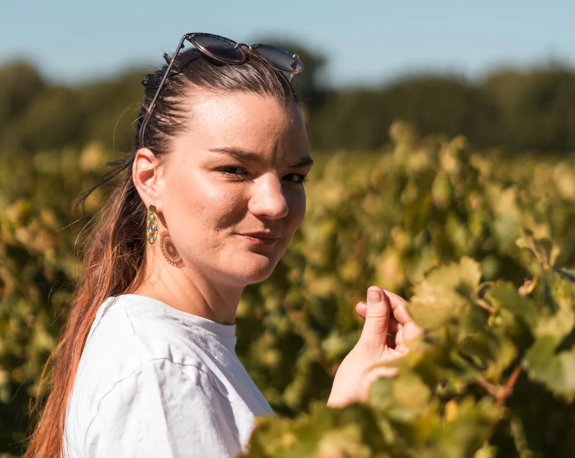 Portrait d'une vigneronne avec des lunettes de soleil dans les cheveux, au milieu des vignes